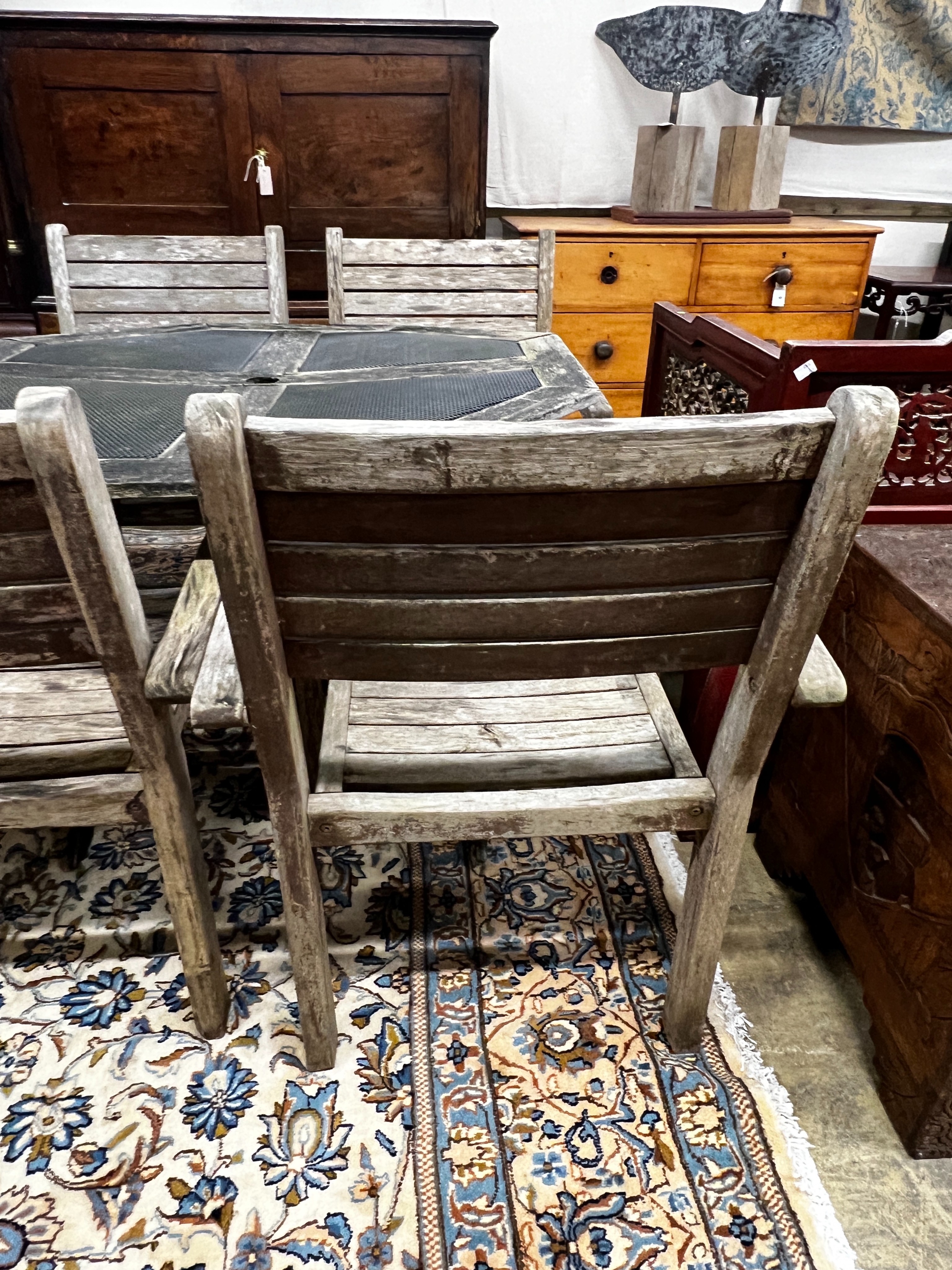 An octagonal weathered teak and mesh garden table, length 103cm, height 74cm together with four teak elbow chairs